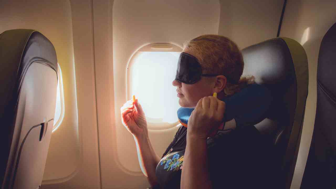 a person is sitting in an airplane seat with their eyes closed