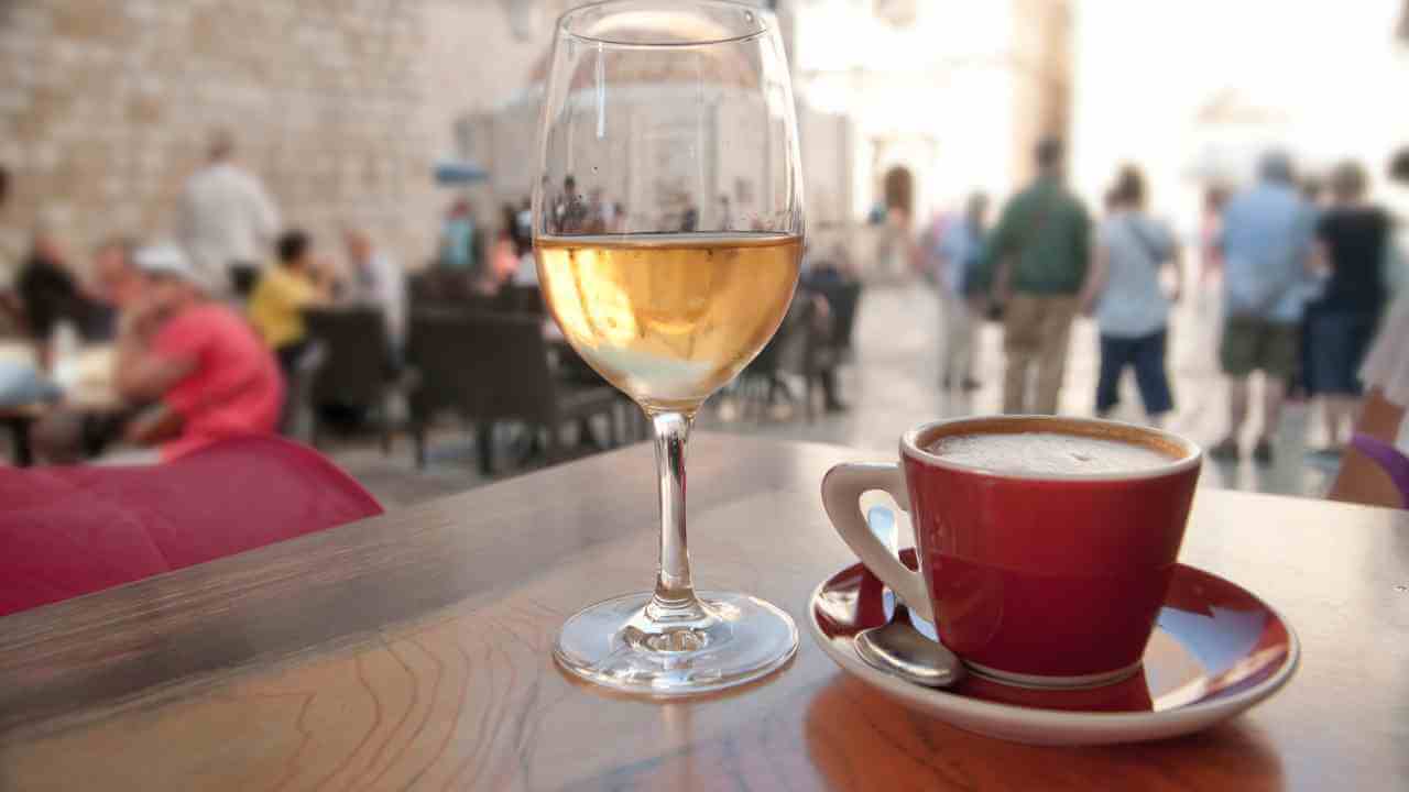 a glass of white wine and a cup of coffee on a table