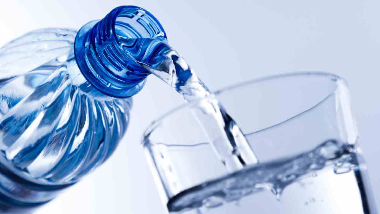 a bottle of water is being poured into a glass