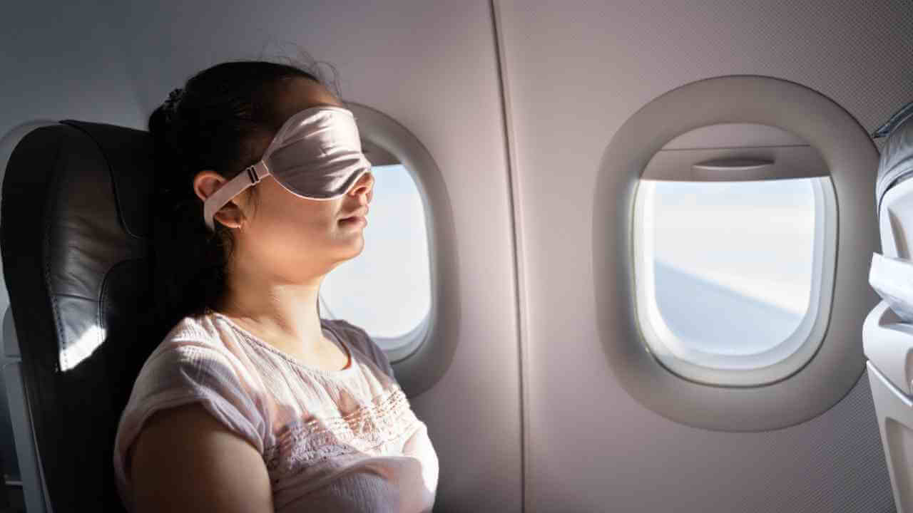 a person wearing an eye mask on an airplane