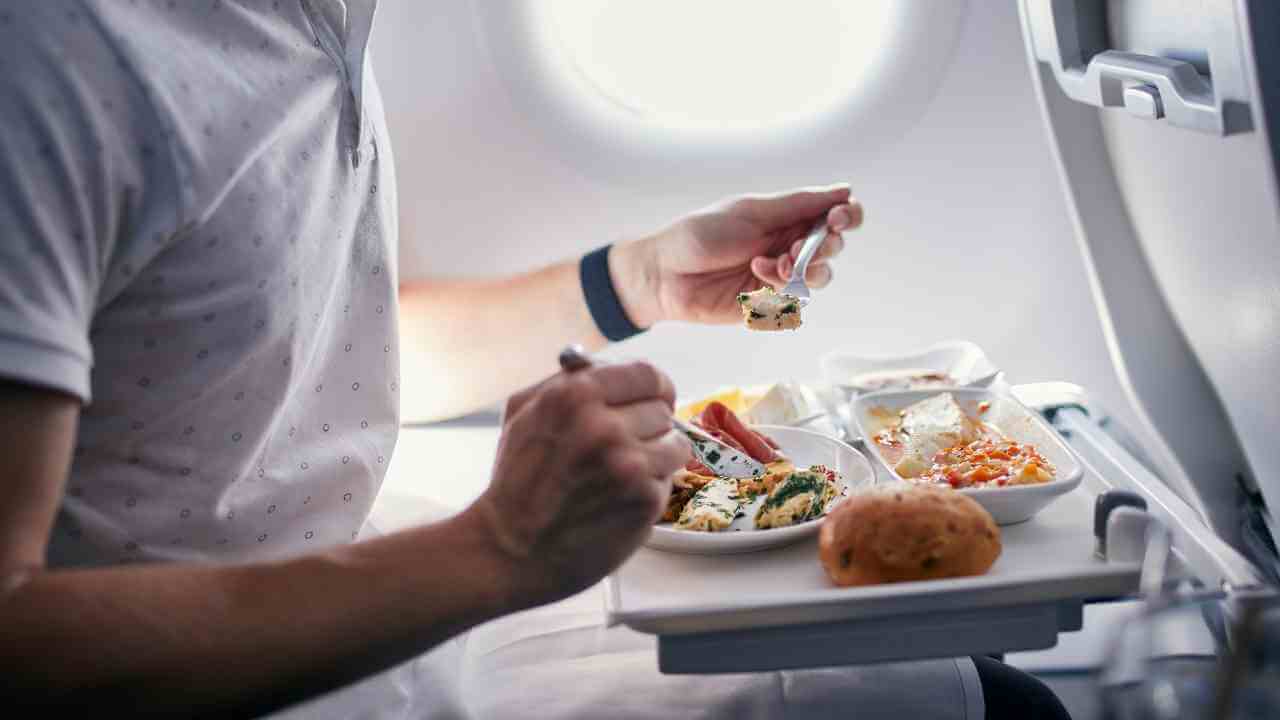 a person is eating food from a tray on an airplane