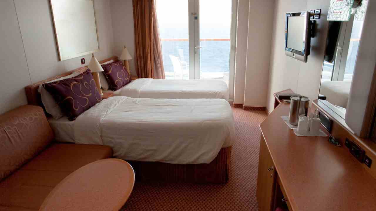 two beds in a room with a view of the ocean