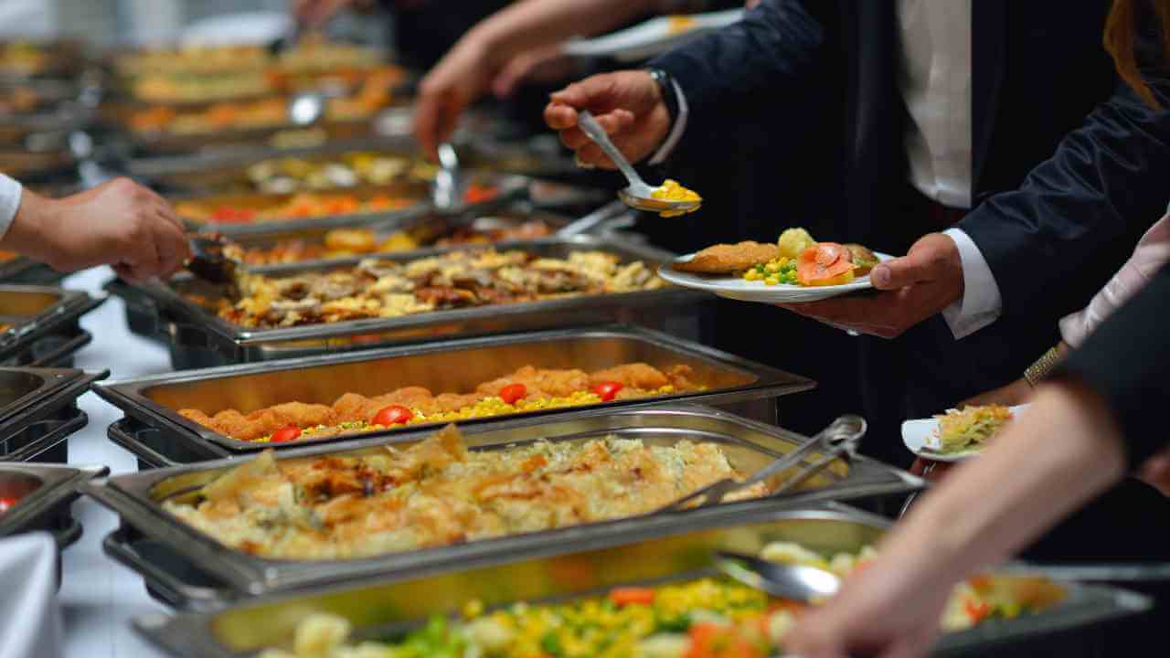 many people are serving food to each other at a buffet