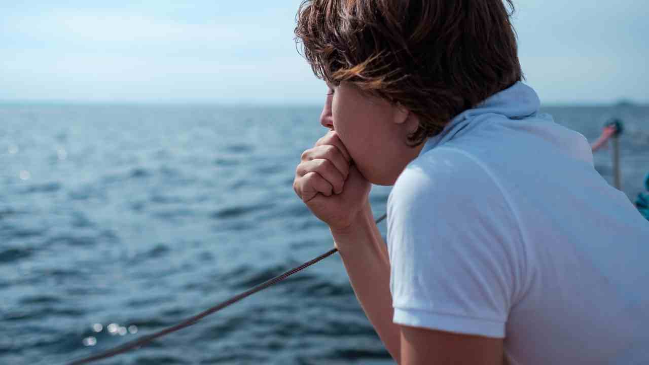 a person sitting on the edge of a boat looking out at the ocean