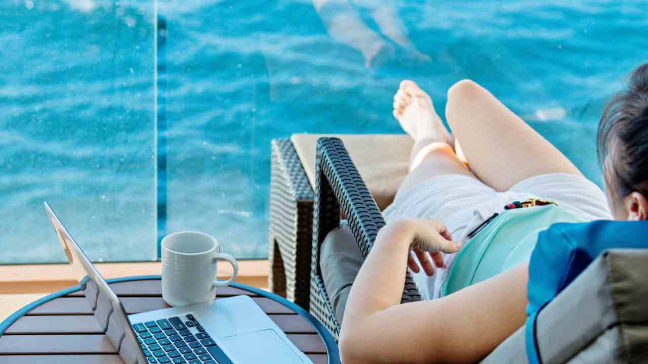 a person sitting in a chair with a laptop on the deck of a cruise ship