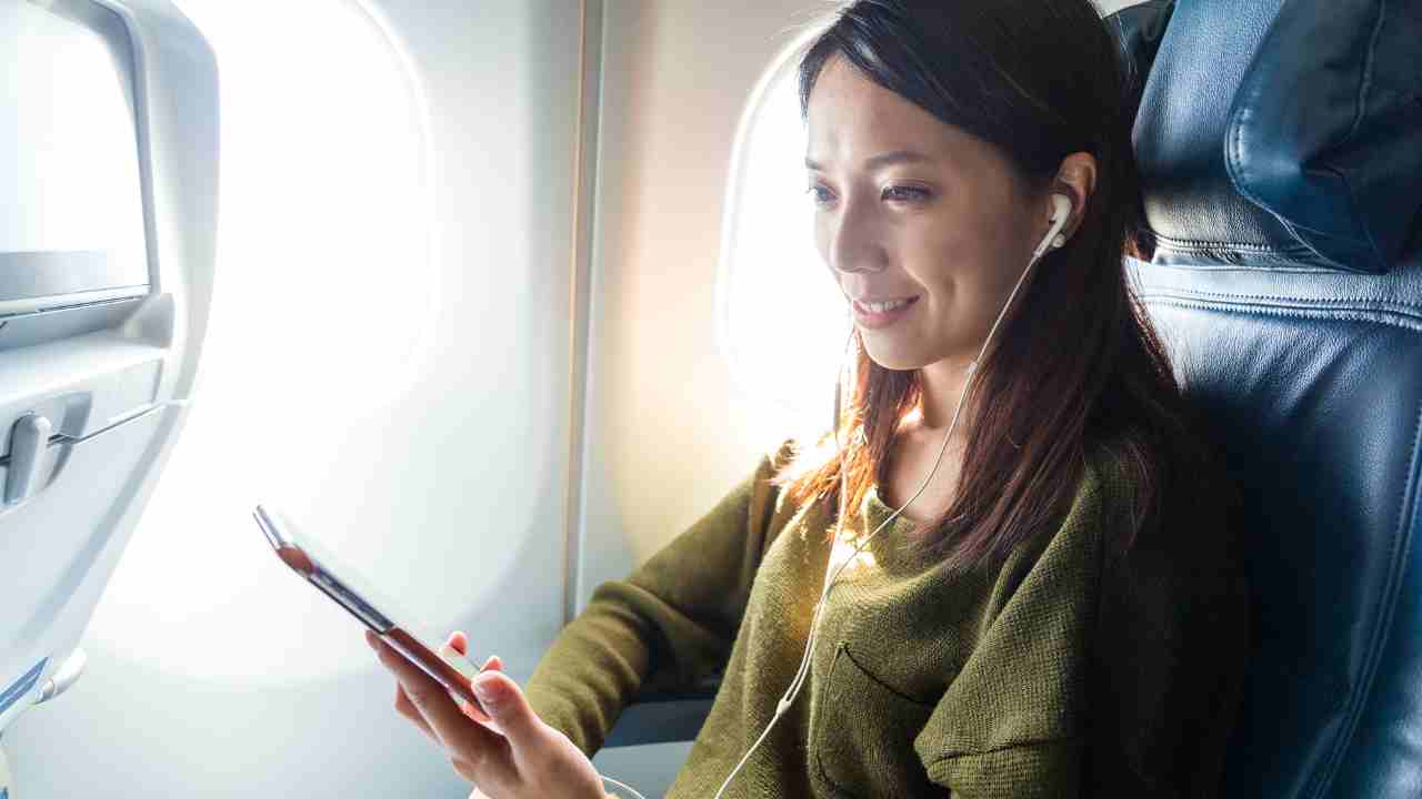 a person is sitting on an airplane and using a cell phone