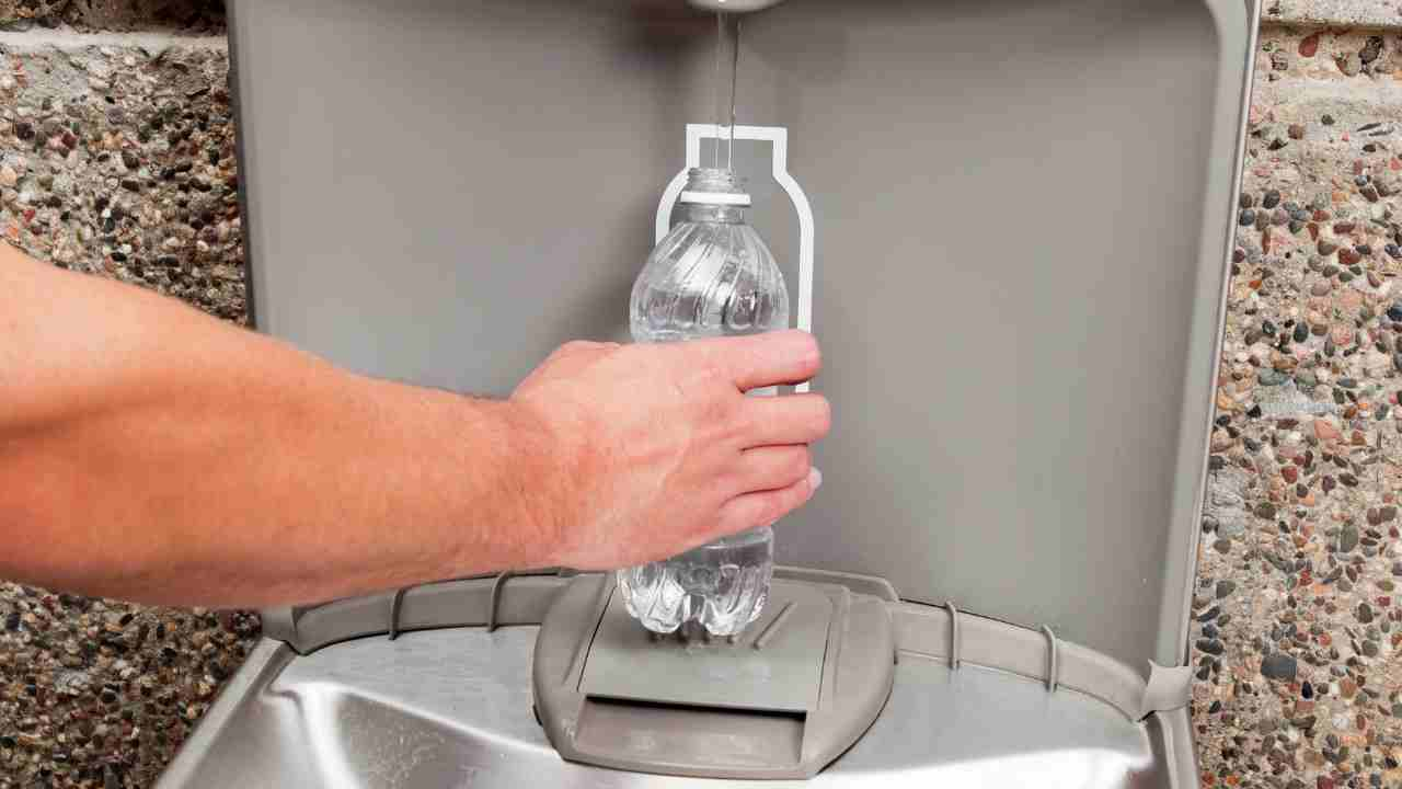 a person is filling up a water bottle from a water fountain