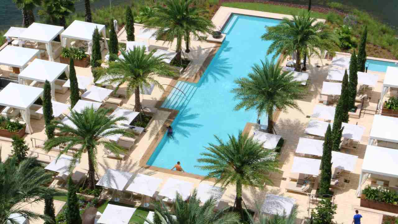 an aerial view of an outdoor pool surrounded by palm trees