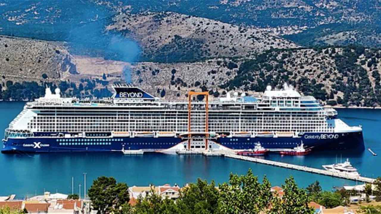 a large cruise ship docked in the water next to a mountain