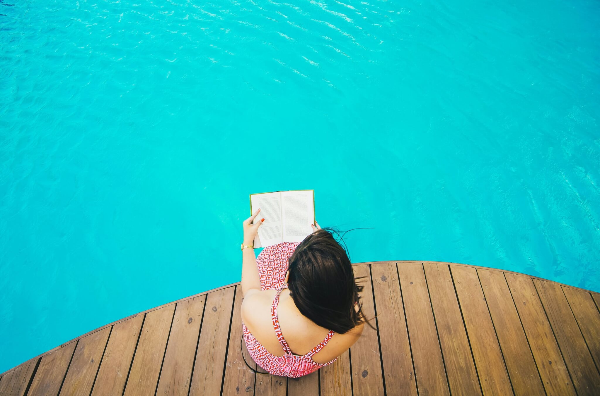 woman reading a book by the pool