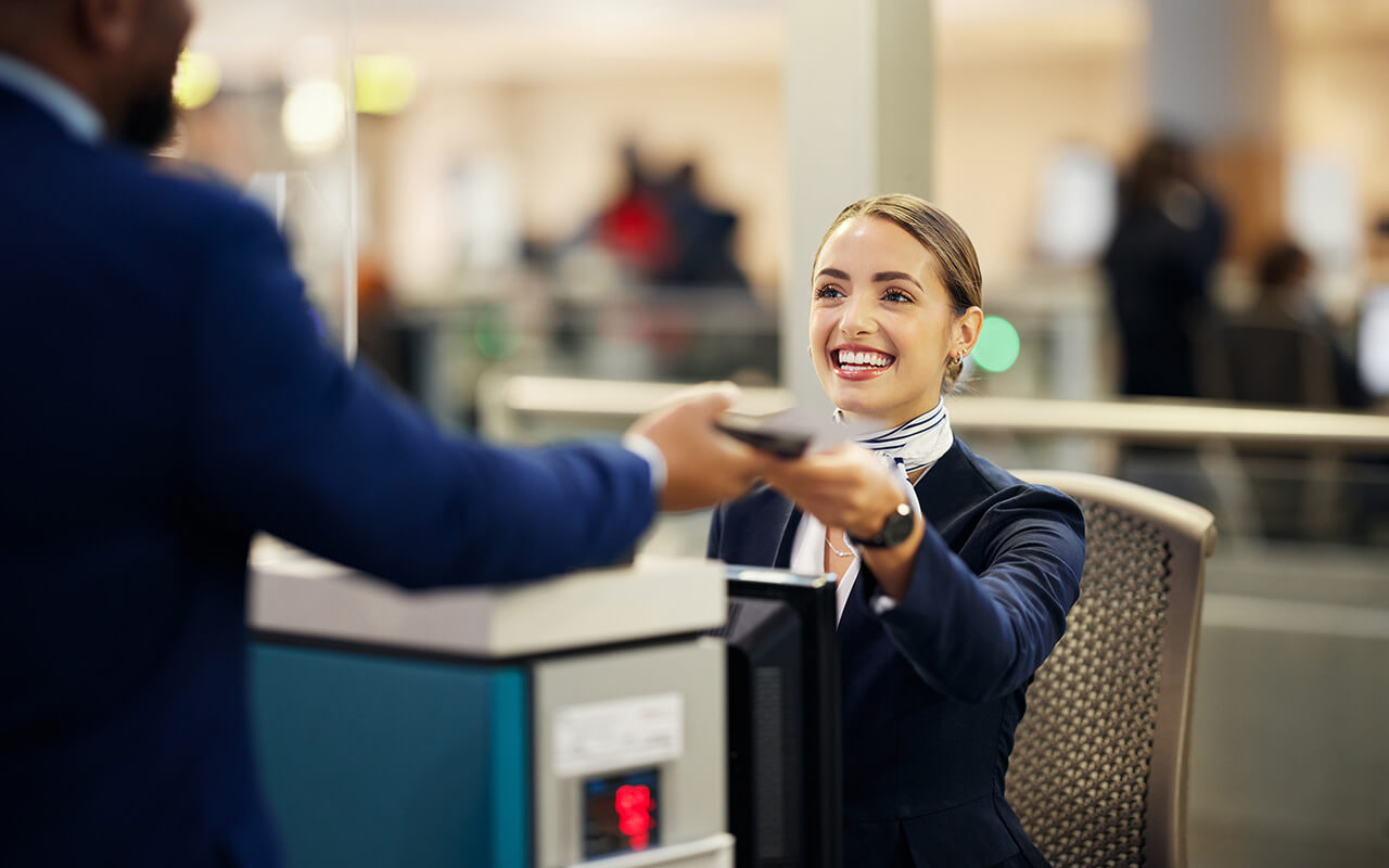 Airline hostess handing passenger their ticket