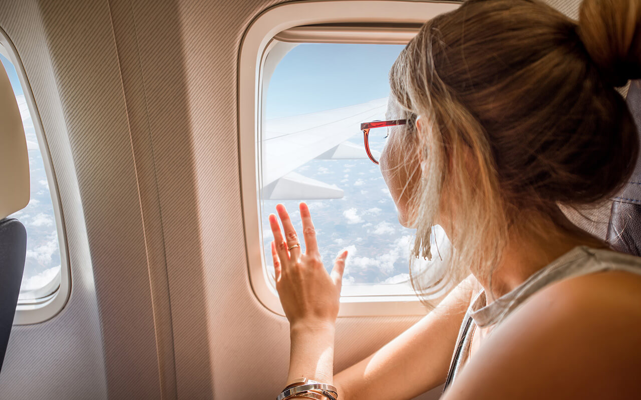 Woman touching the window on an airplane