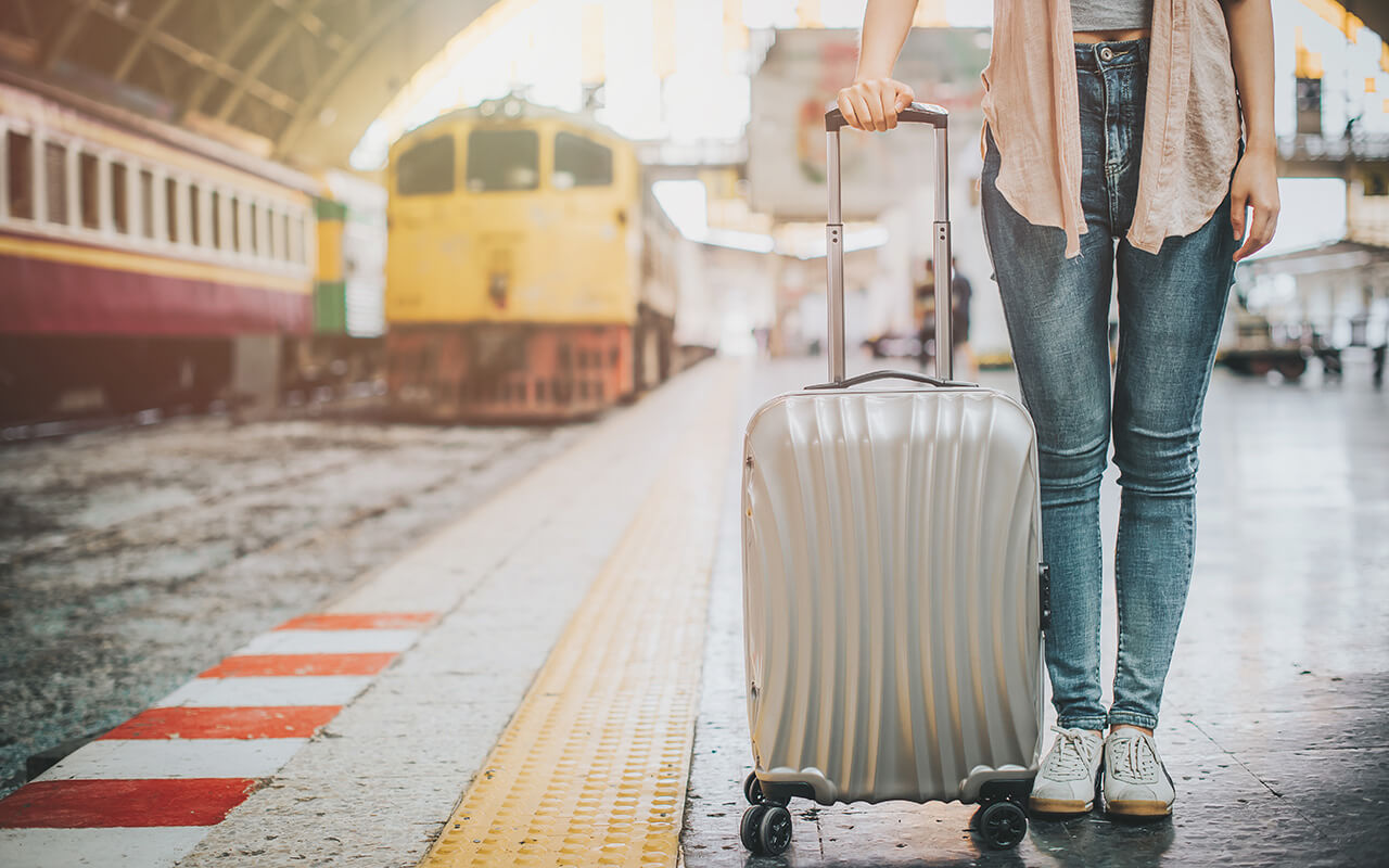 Person carrying their luggage near a train