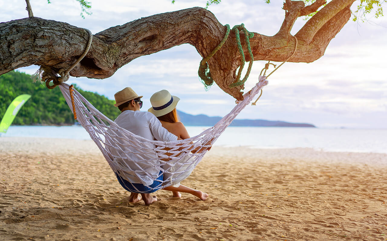 Couple sitting on a hammock on the beach