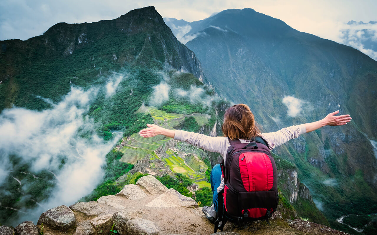 Woman spreading out her arms while looking at a beautiful landscape