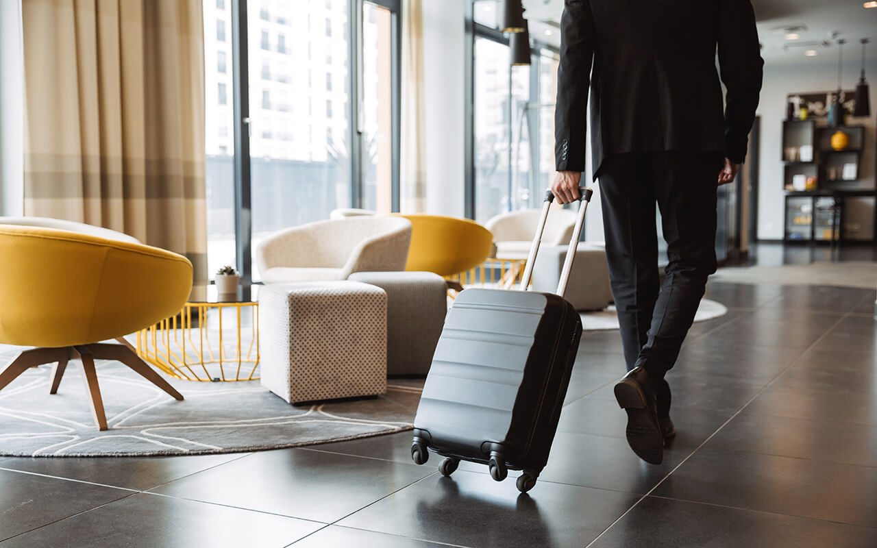 Man wheeling his luggage through a hotel