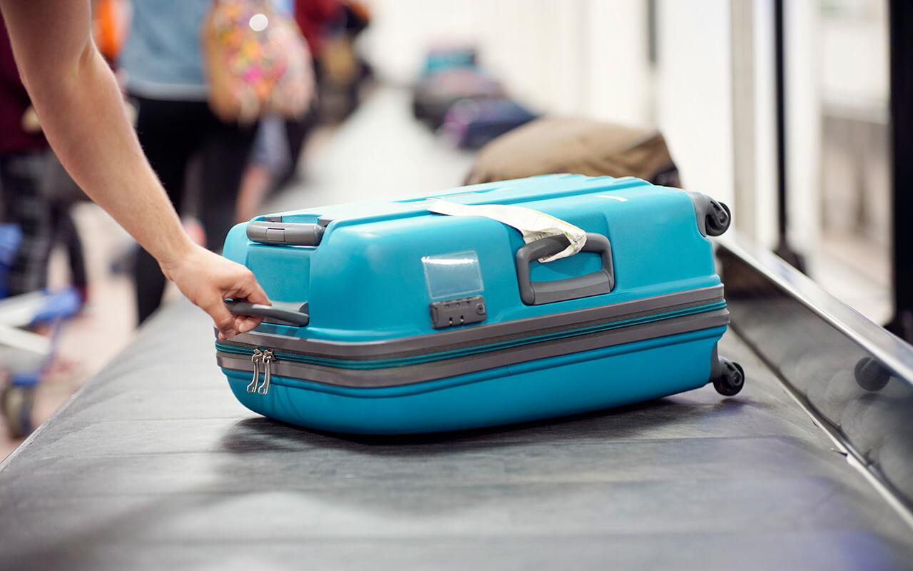 person picking up luggage from an airport 