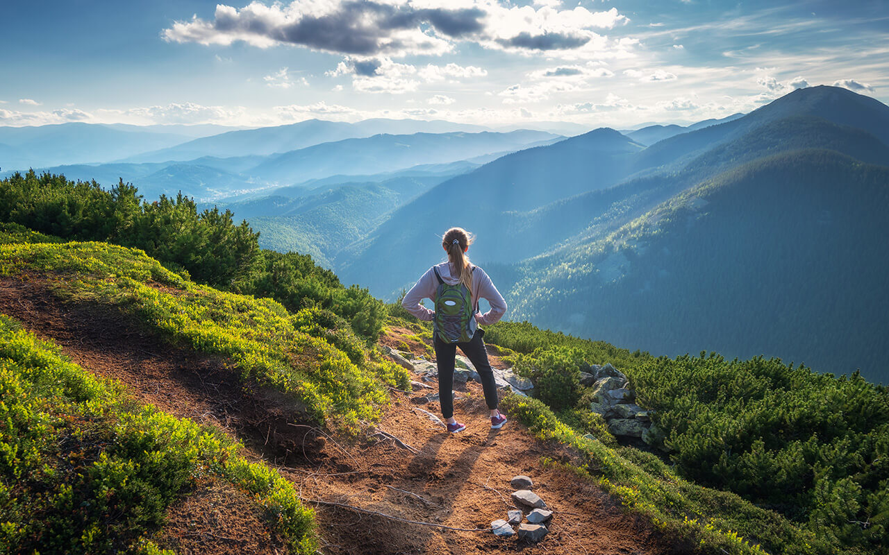 Woman with a backpack looking at mountains on a hike