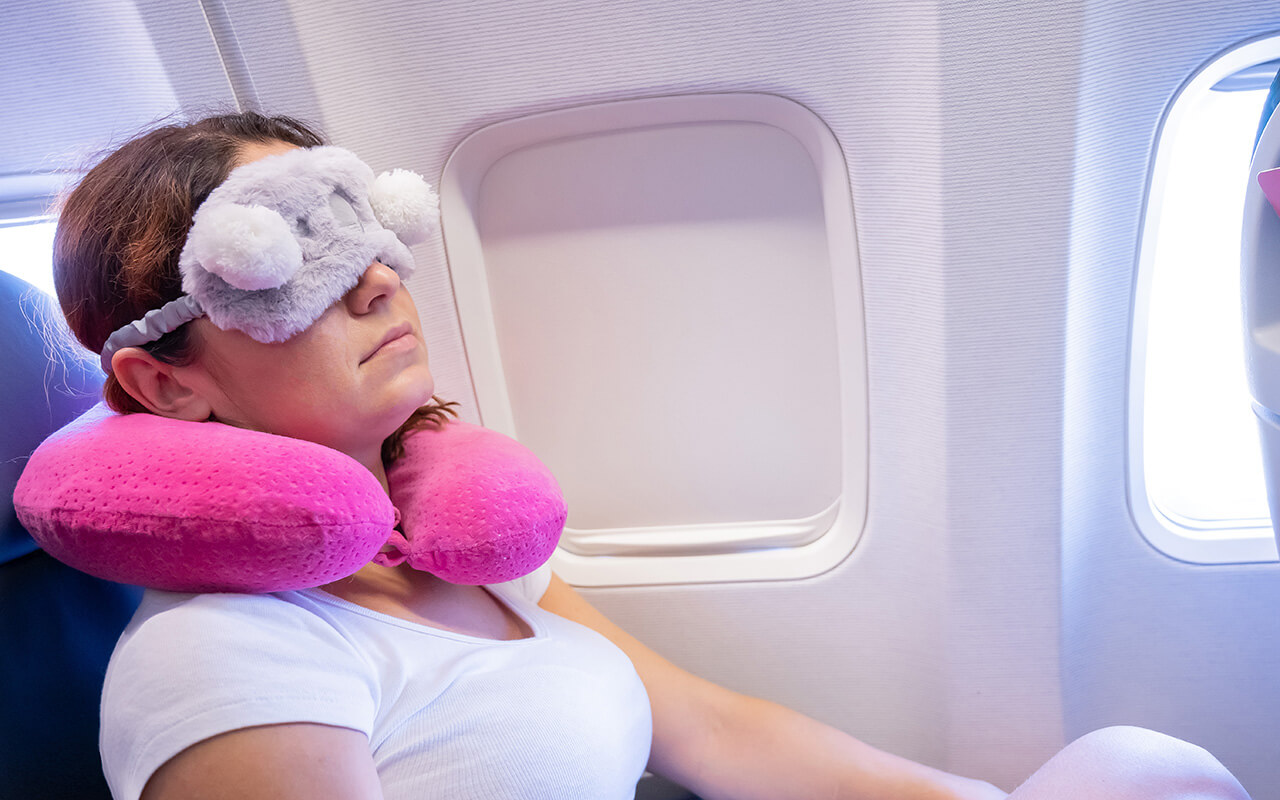 woman with neck pillow sleeping on plane