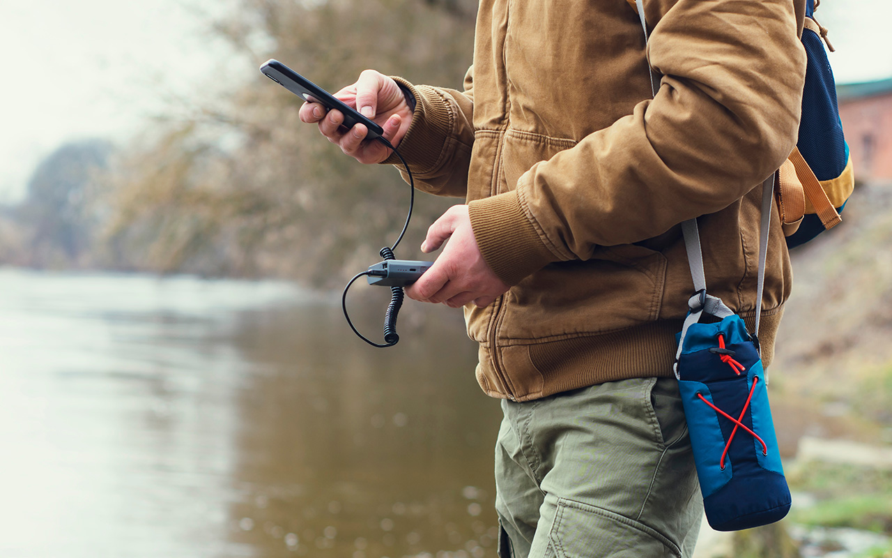 Man using a portable phone charger while hiking