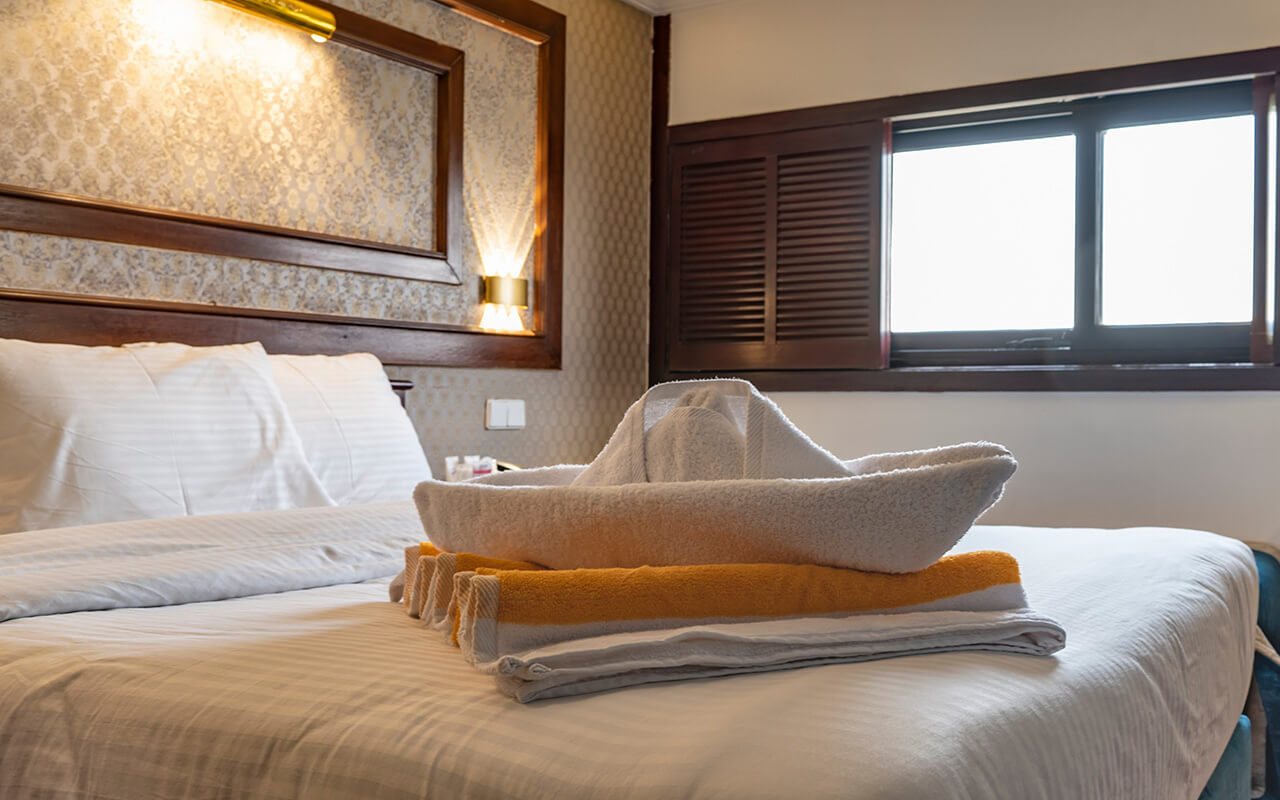 The bed is made in the cabin of a cruise ship.