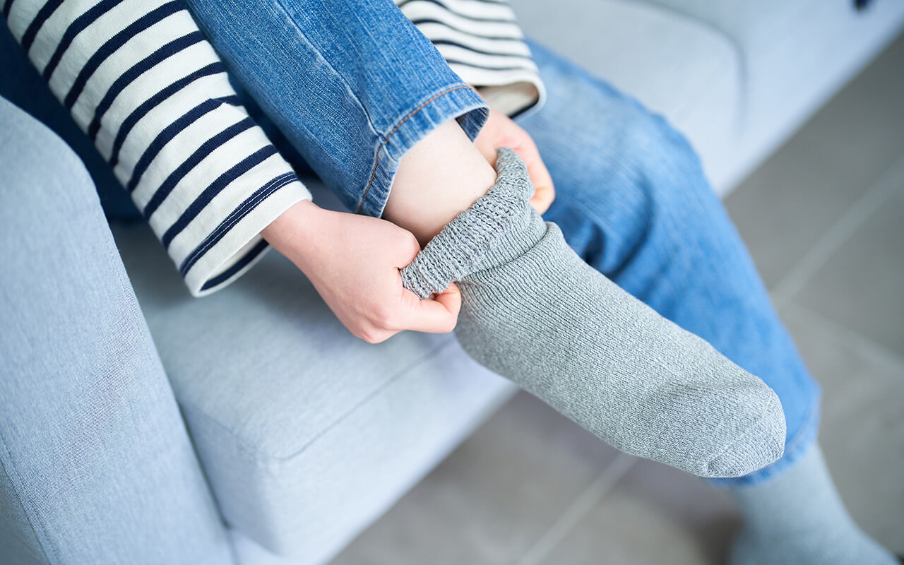 Woman putting socks on her cold feet.