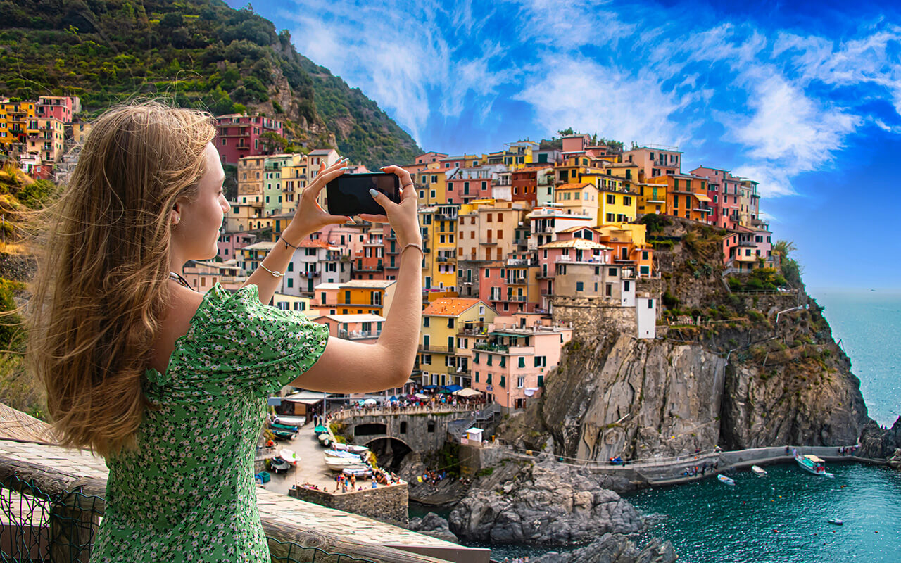 A tourist girl taking a picture of Manarola, Liguria, Italy
