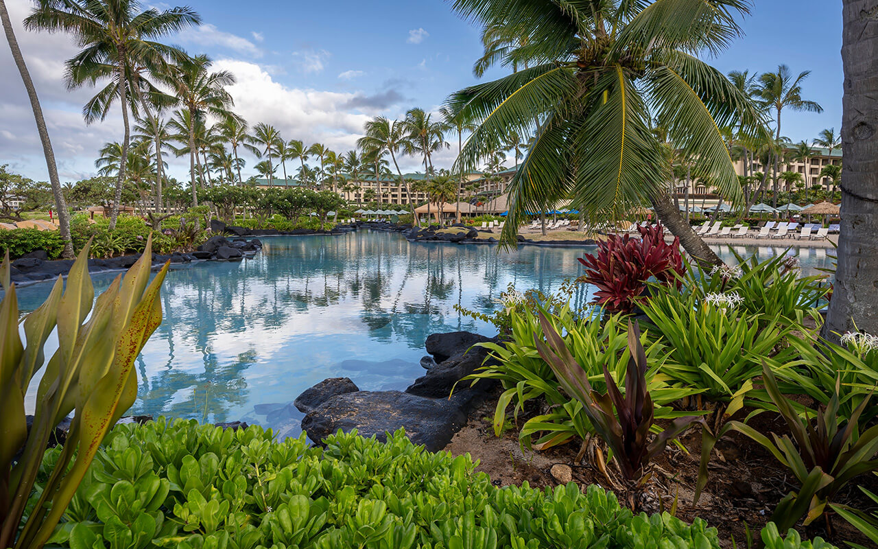 Palm trees reflect in the beautiful turquoise water of one of the luxurious swimming pools at the Grand Hyatt Kauai Resort and Spa in Koloa, Hawaii.