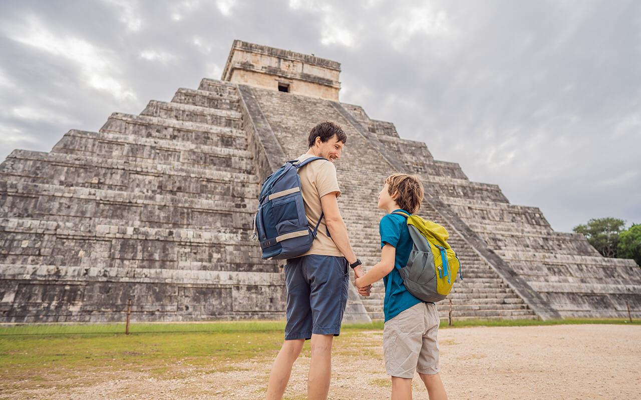 Father and son tourists observing the old pyramid and temple of the castle of the Mayan architecture known as Chichen Itza