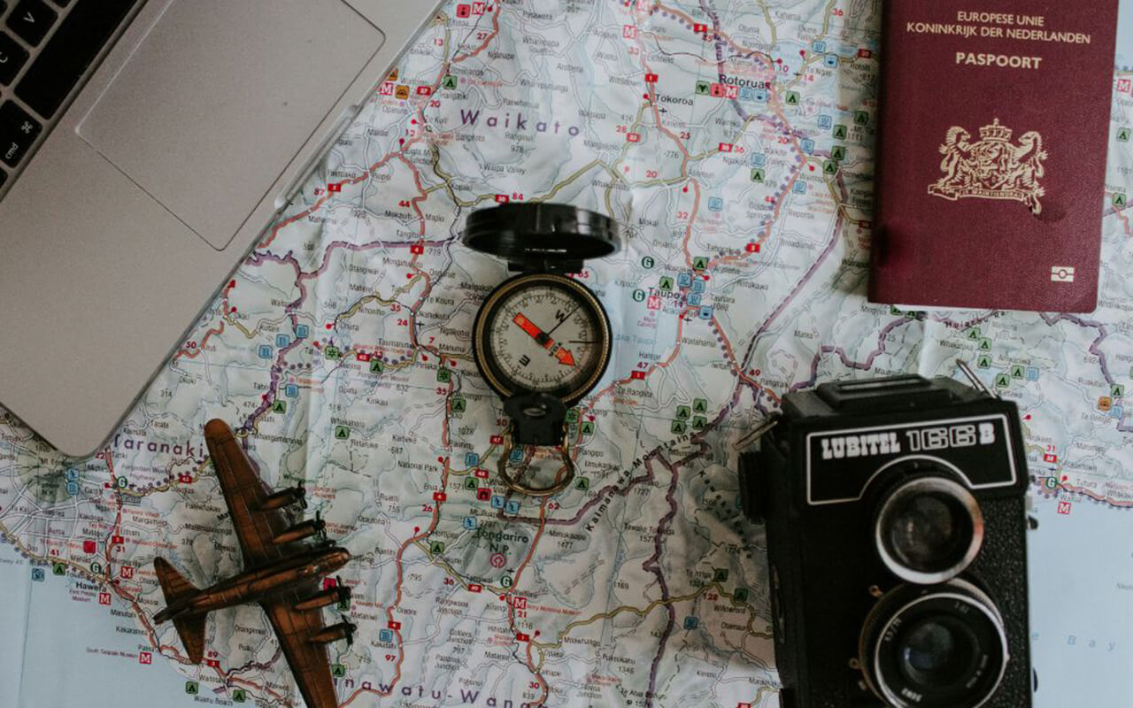 Map, passport, camera, compass, computer and miniature plane