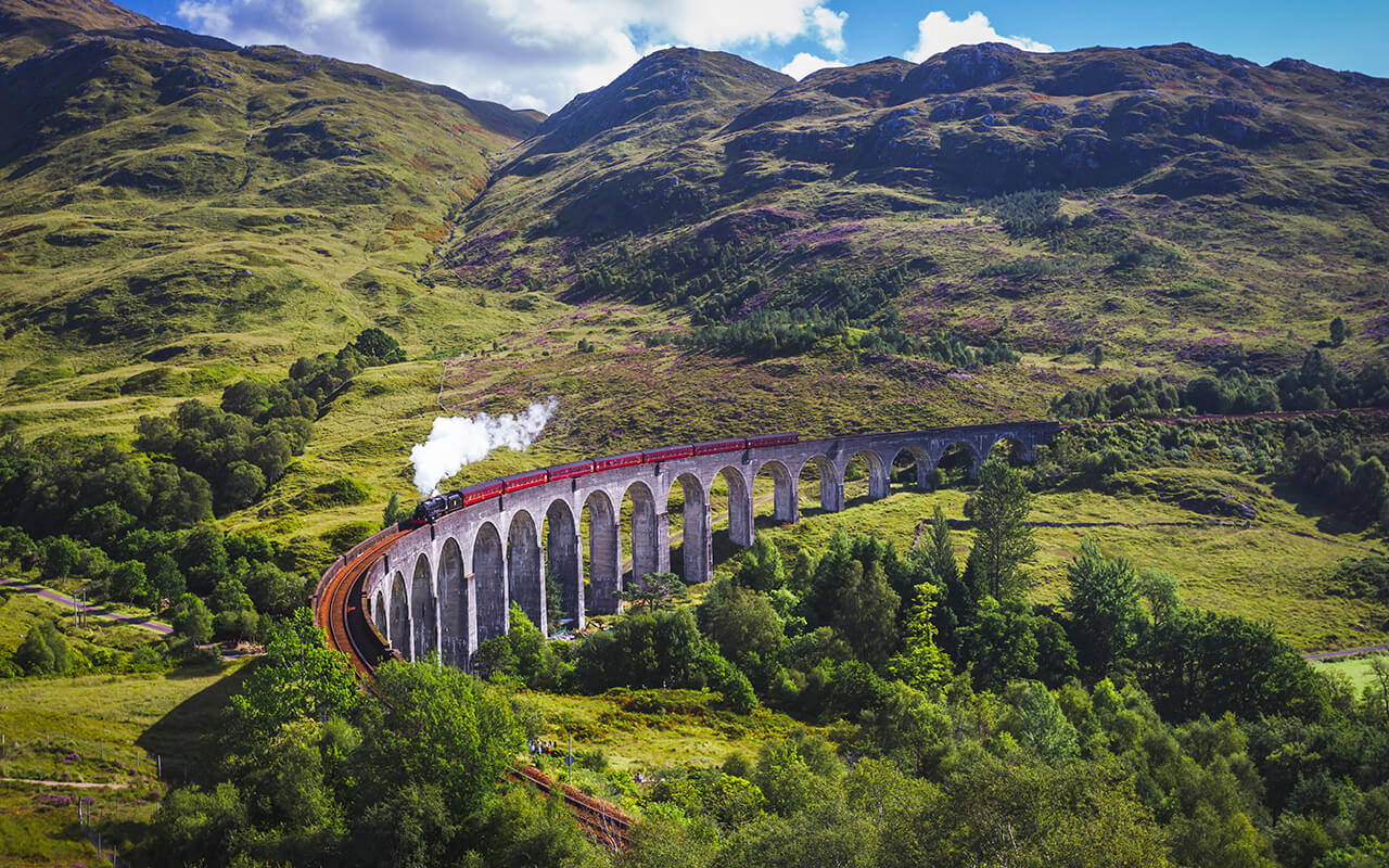 Glenfinnan Railway Viaduct in Scotland with the Jacobite steam train passing over.