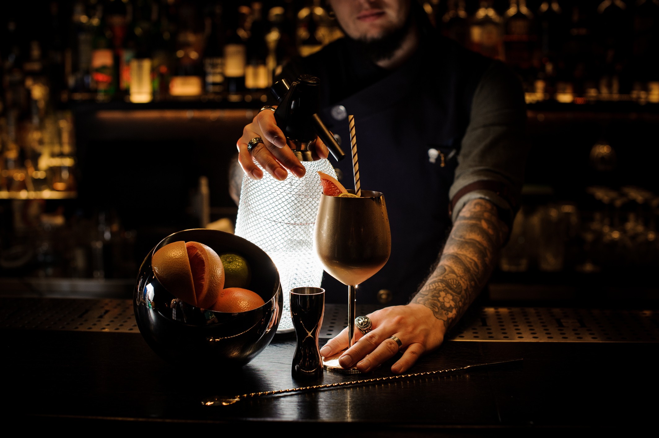 Bartender adding cocktail from the syphon to the copper cup.