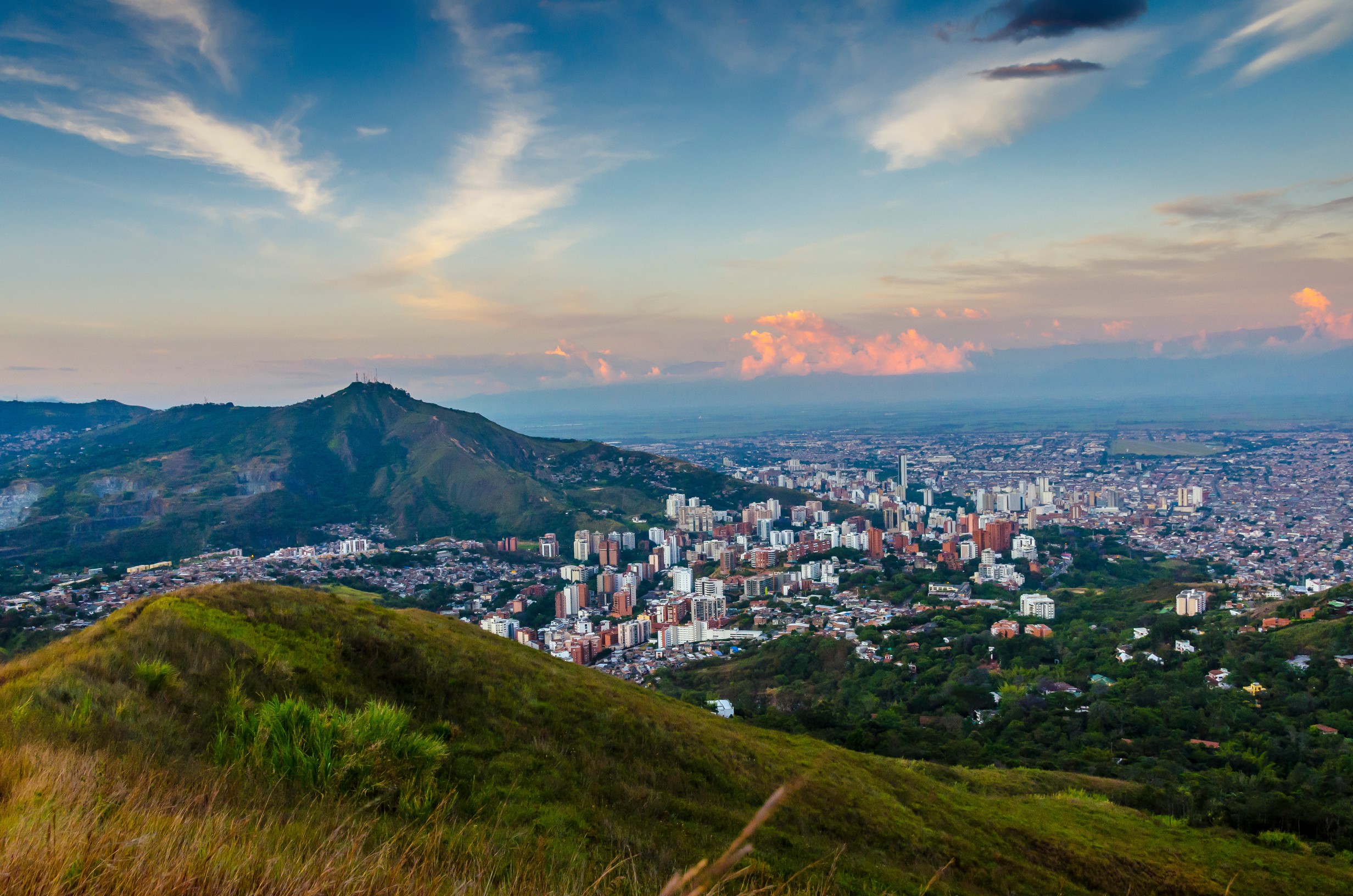 Vibrant city view of Cali, Colombia with colorful buildings, palm trees, and sunny skies.