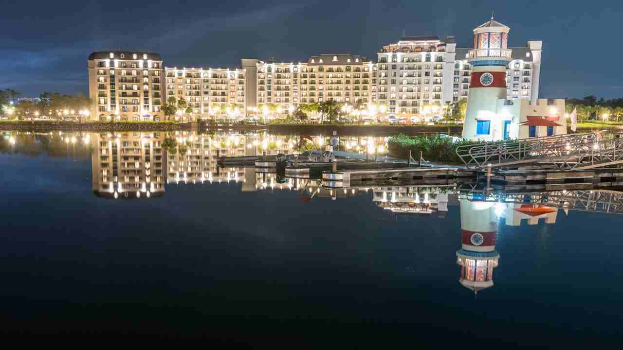 a night time view of a harbor with a lighthouse in the foreground