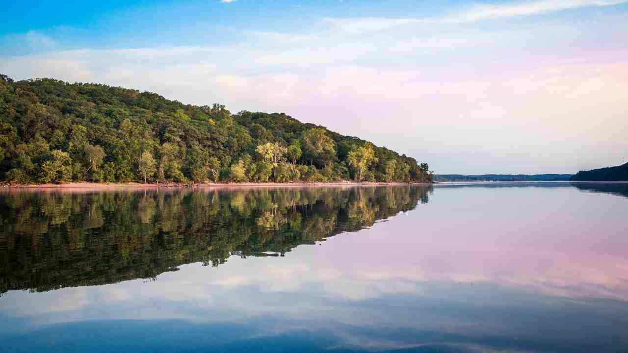 a calm lake surrounded by trees at sunset