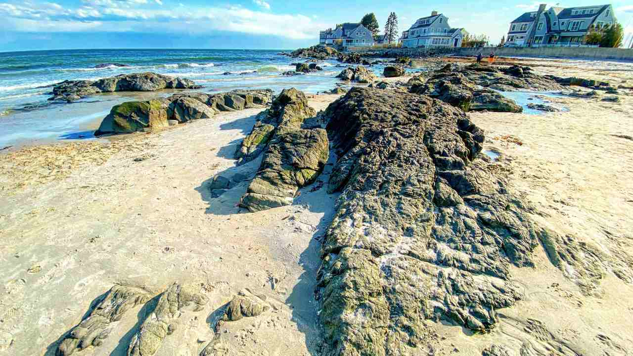 an aerial view of a rocky beach with houses on the shore