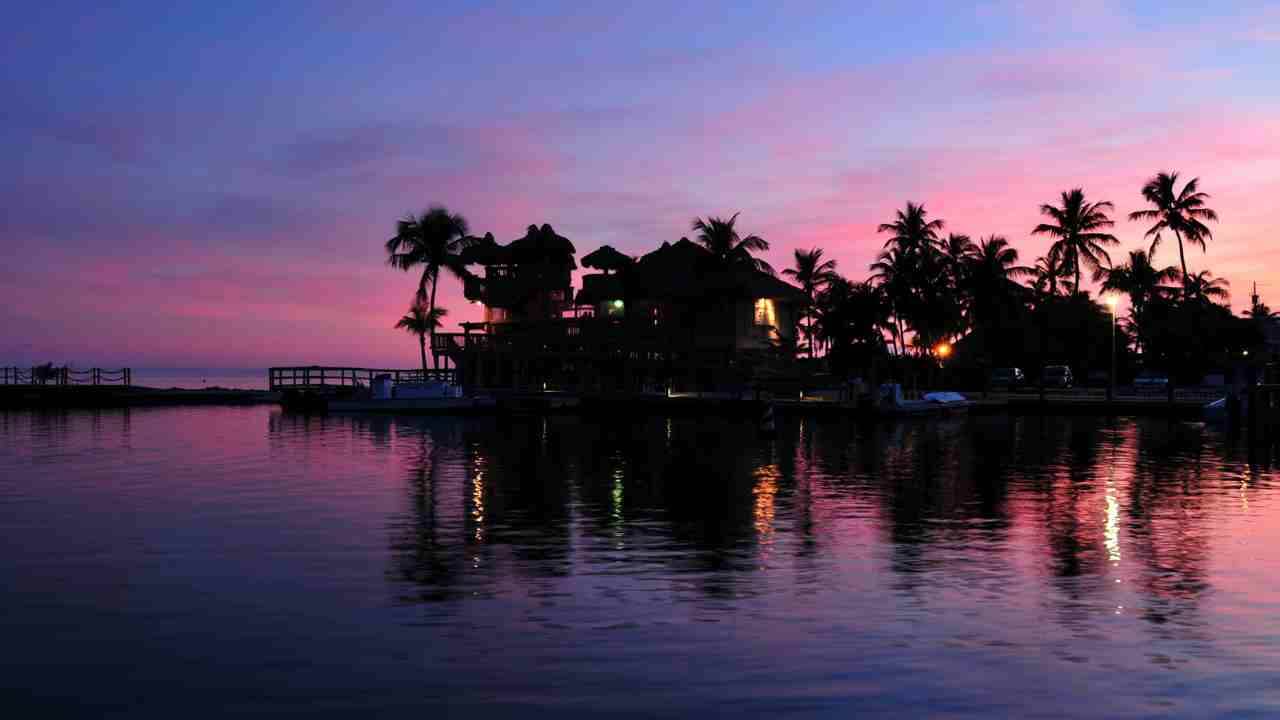 a pink and purple sunset is reflected in the water