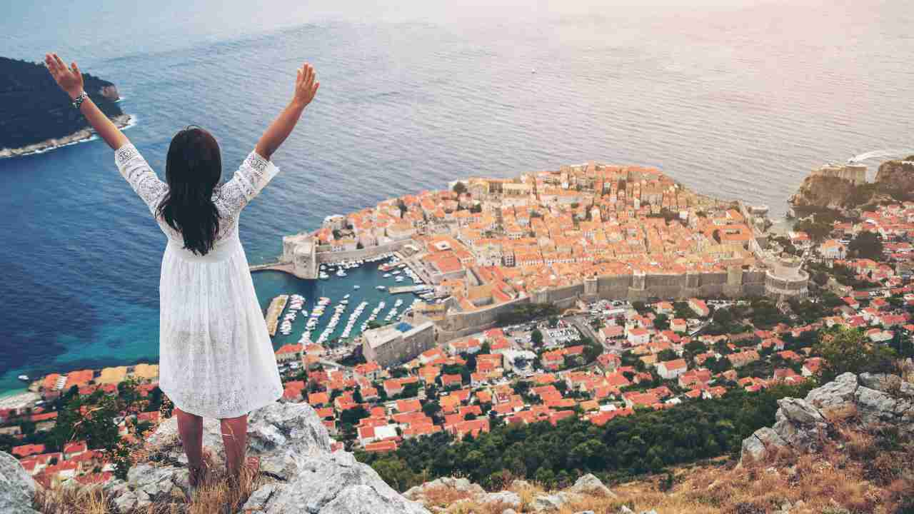 person standing on the edge of a cliff overlooking the city of Dubrovnik, Croatia.