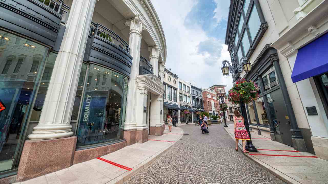 people are walking down the street in front of shops