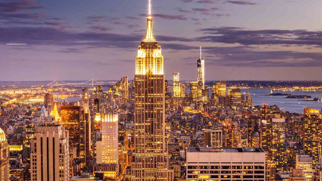 the empire state building is lit up at dusk in new york city