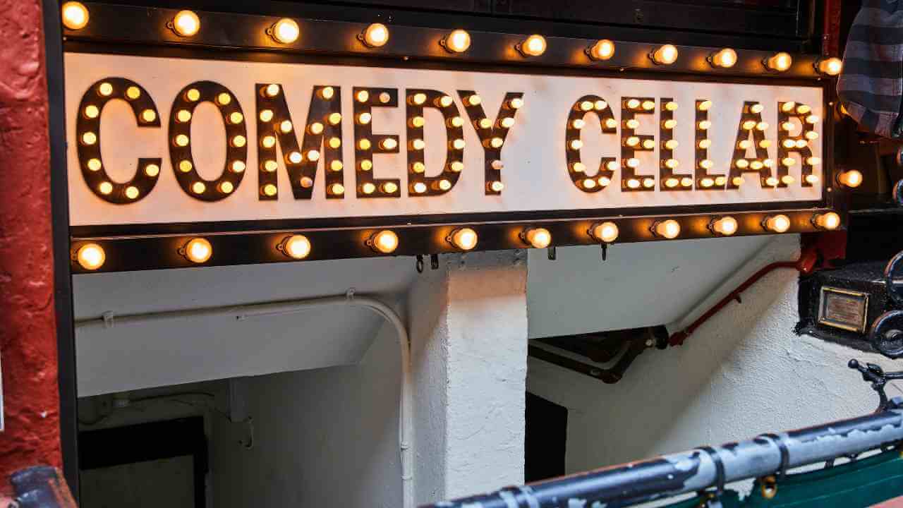 a sign for comedy cellar on the side of a building