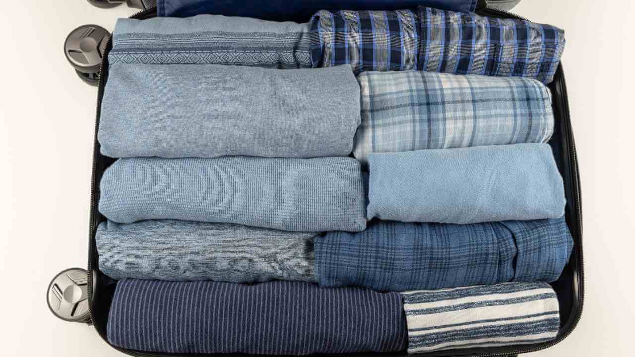 an open suitcase filled with blue and white clothing