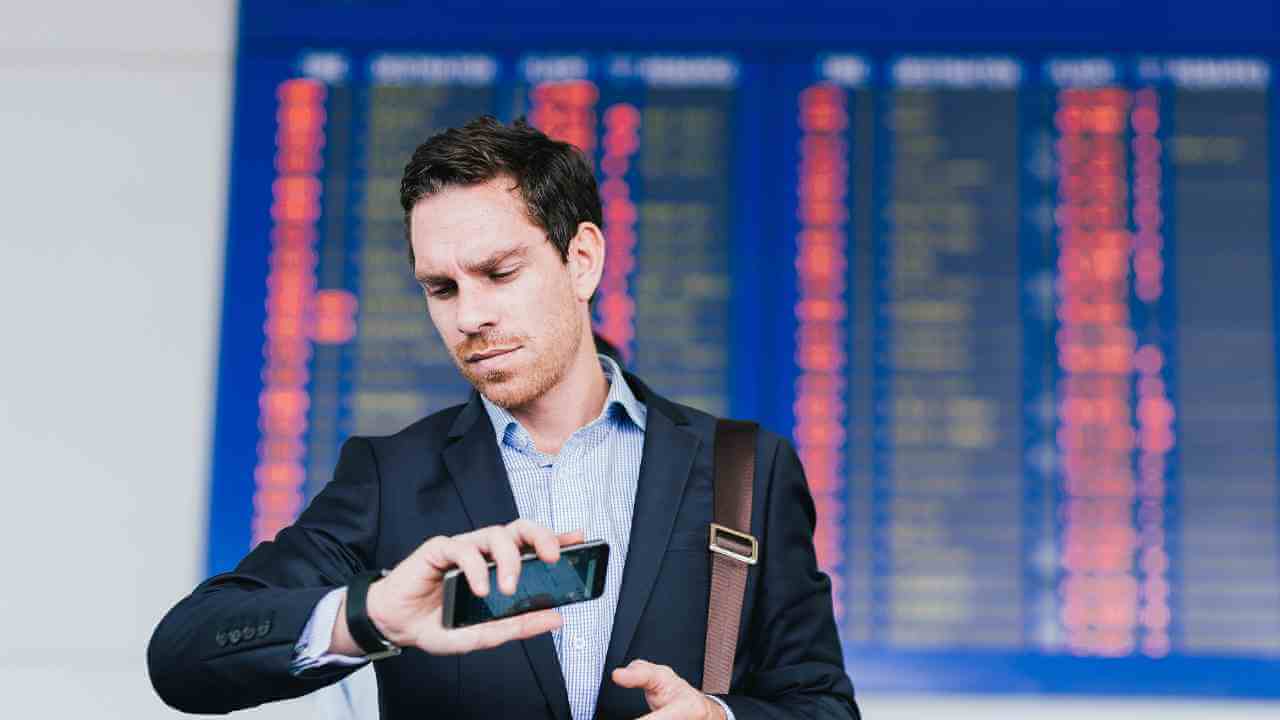 a person in a suit looking at their cell phone in an airport