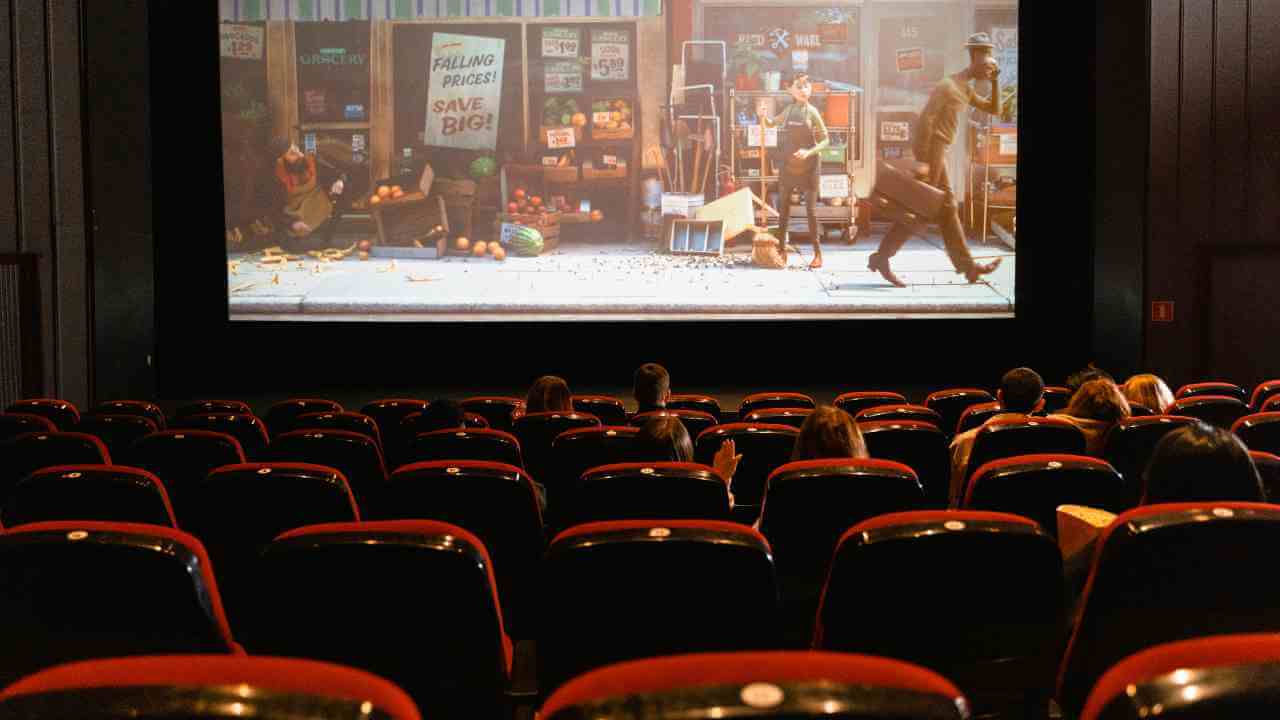 a movie theater with people sitting in red chairs