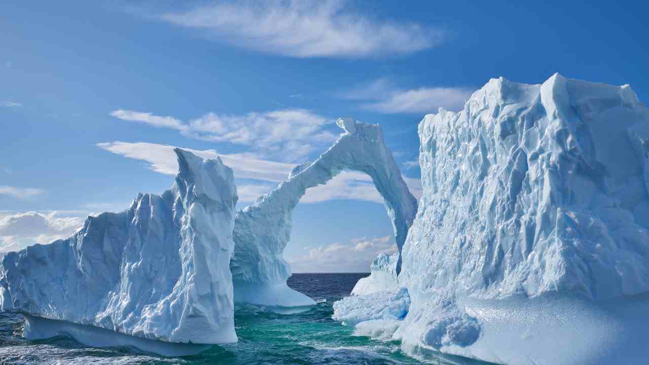 icebergs in the ocean with a blue sky in the background