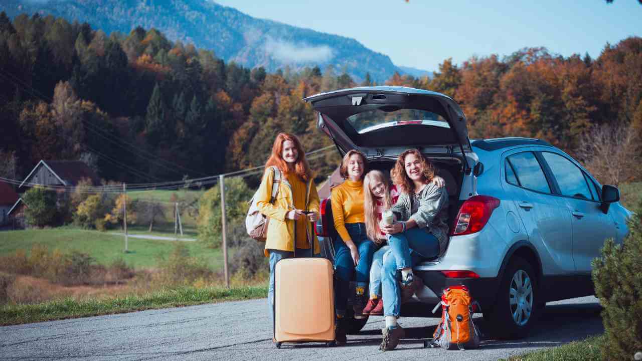 three individuals sitting in the trunk of a car with their luggage