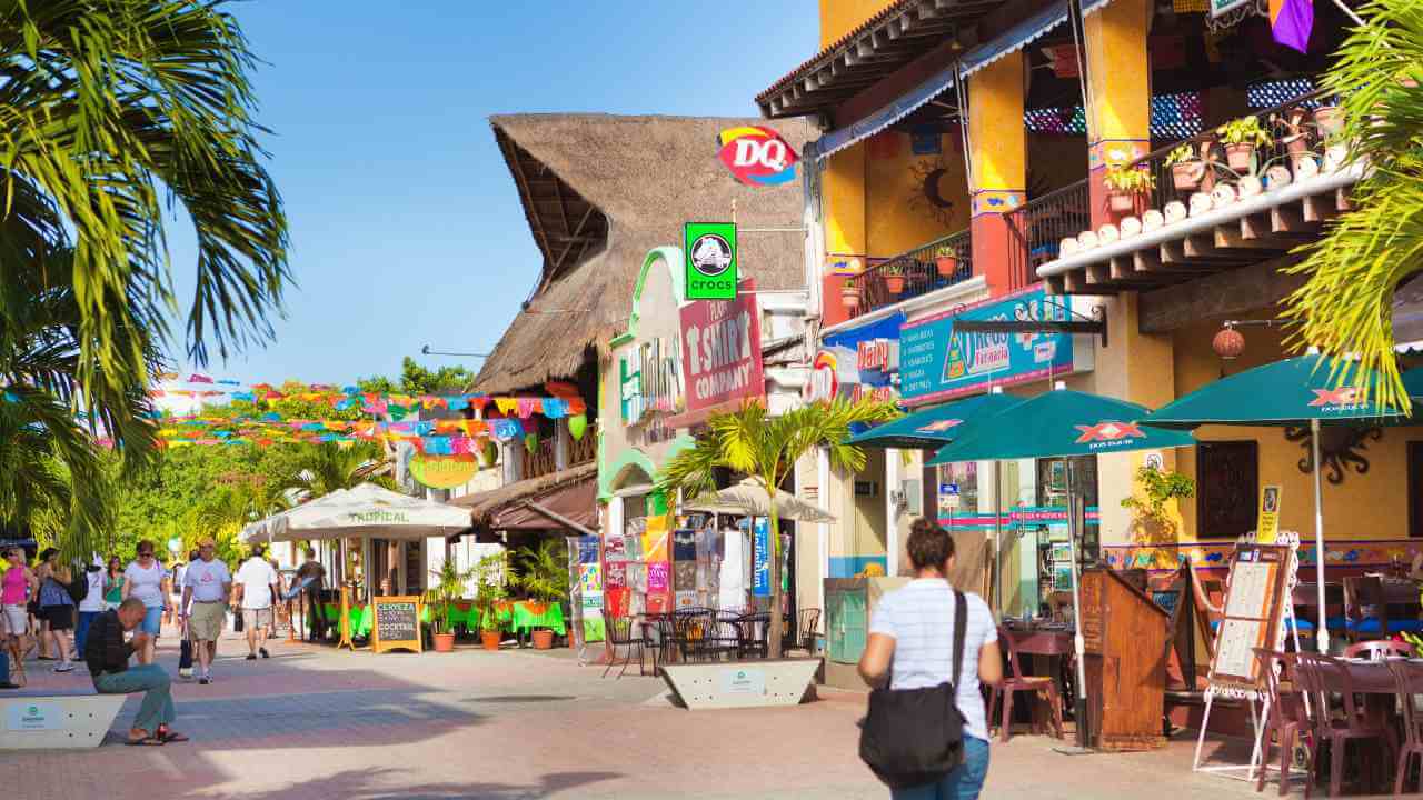 Tourists walk down a street lined with shops and restaurants