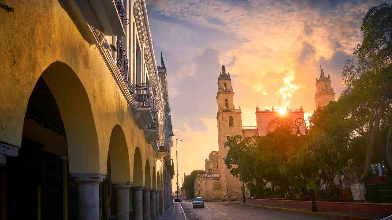 the sun is setting over a city street in mexico