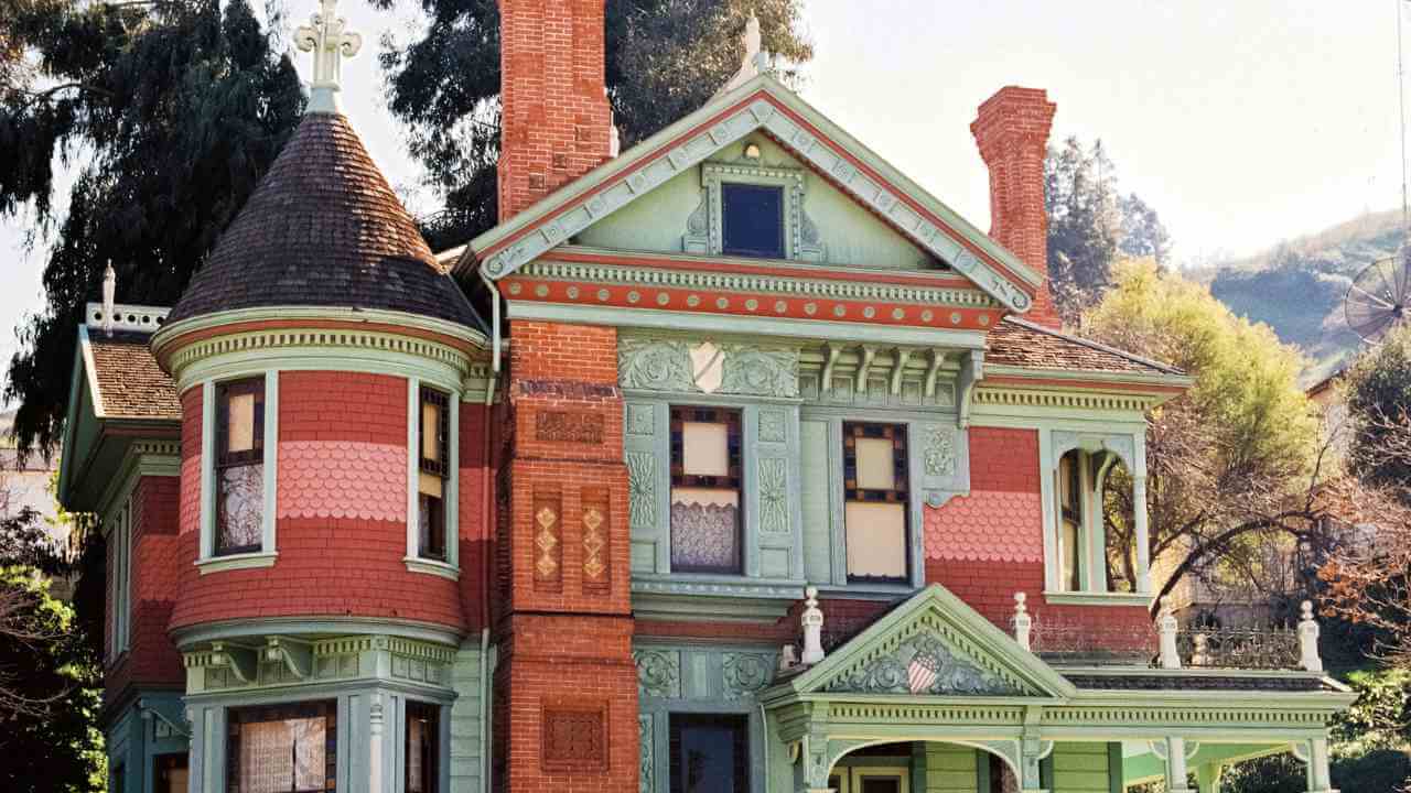 an old victorian style house with green and red trim