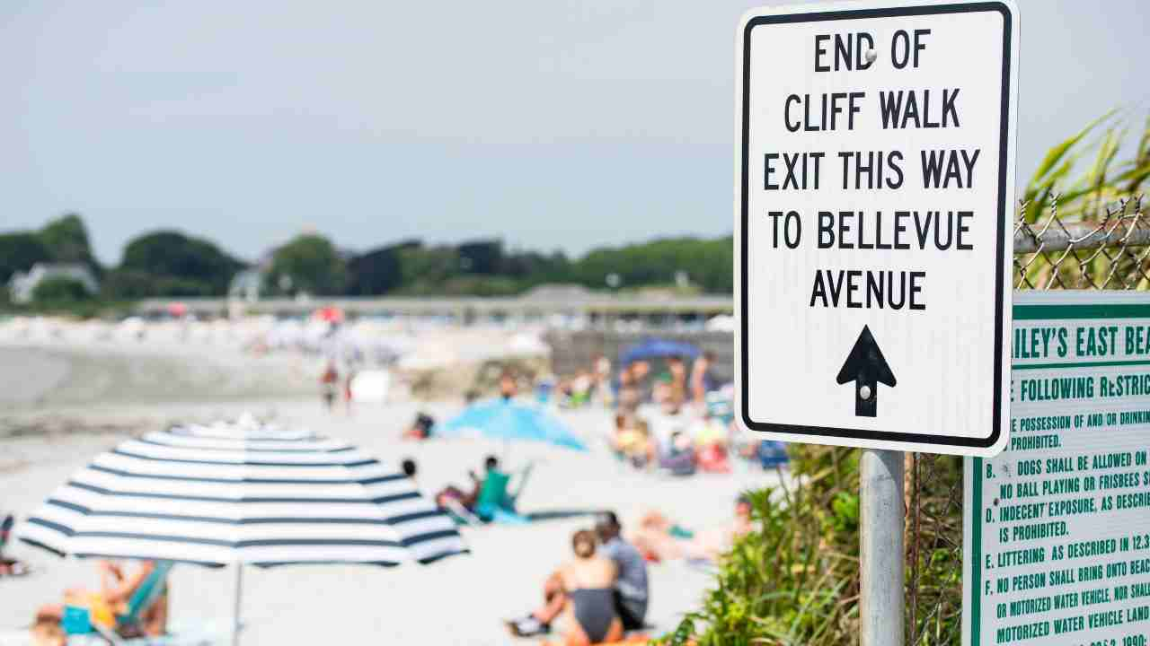 a sign on the beach that says "end of cliff walk exit this way to bellevue avenue"